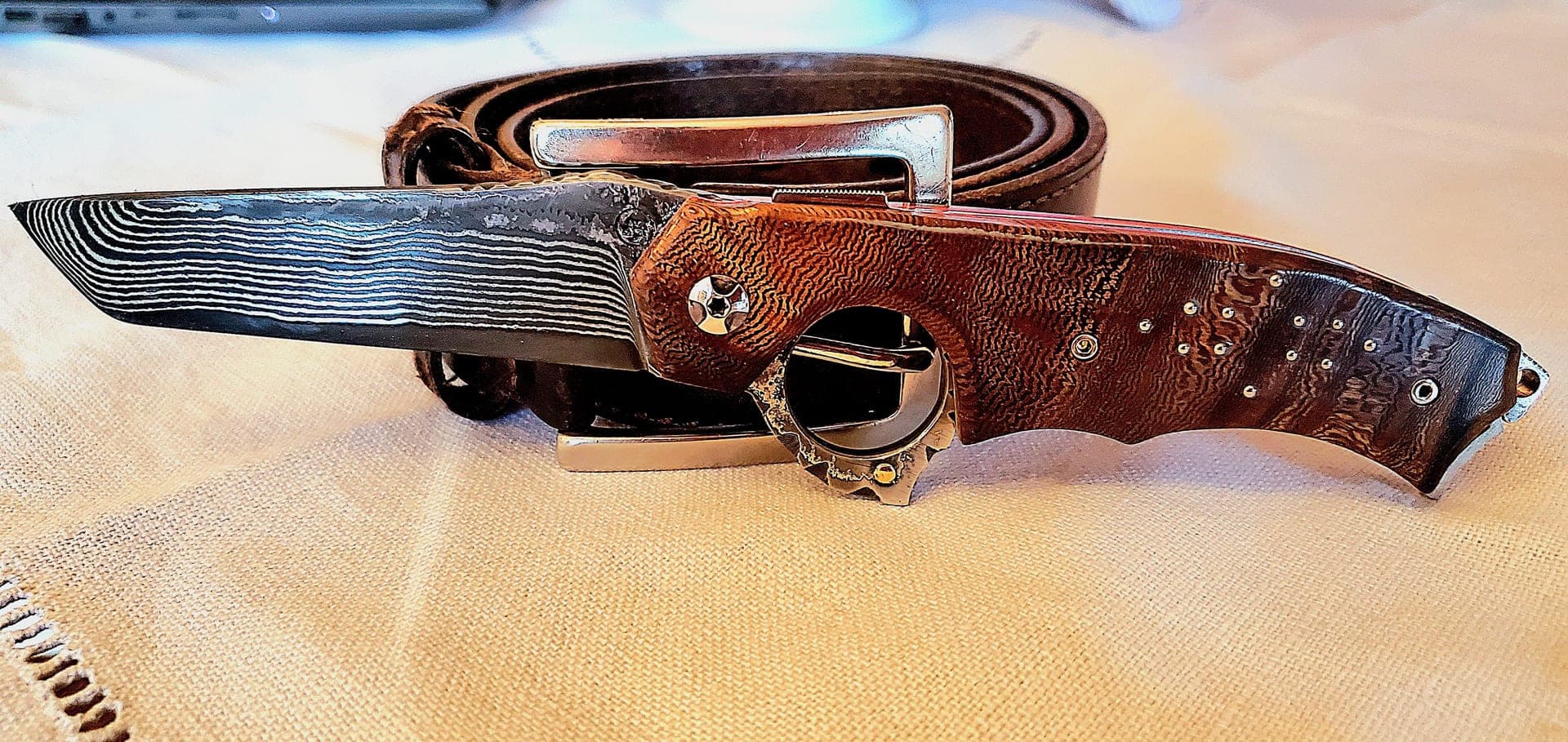 L'Archétype open, damascus blade, precious wood handle and reverse-opening ring at the junction of the handle.
