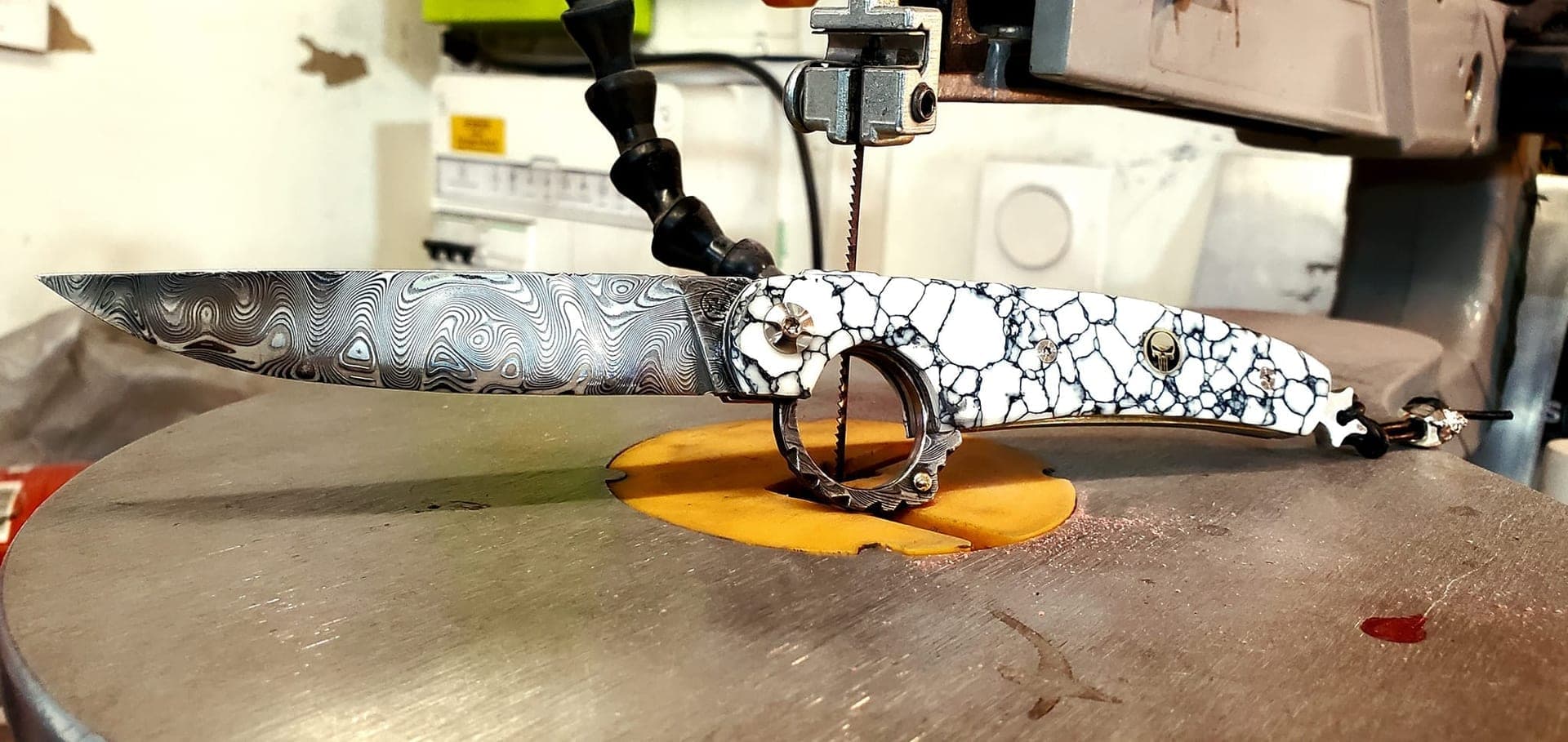 Le Fhiers, couteau à ouverture inversée, en cours de façonnage sur la scie à ruban de l'atelier.