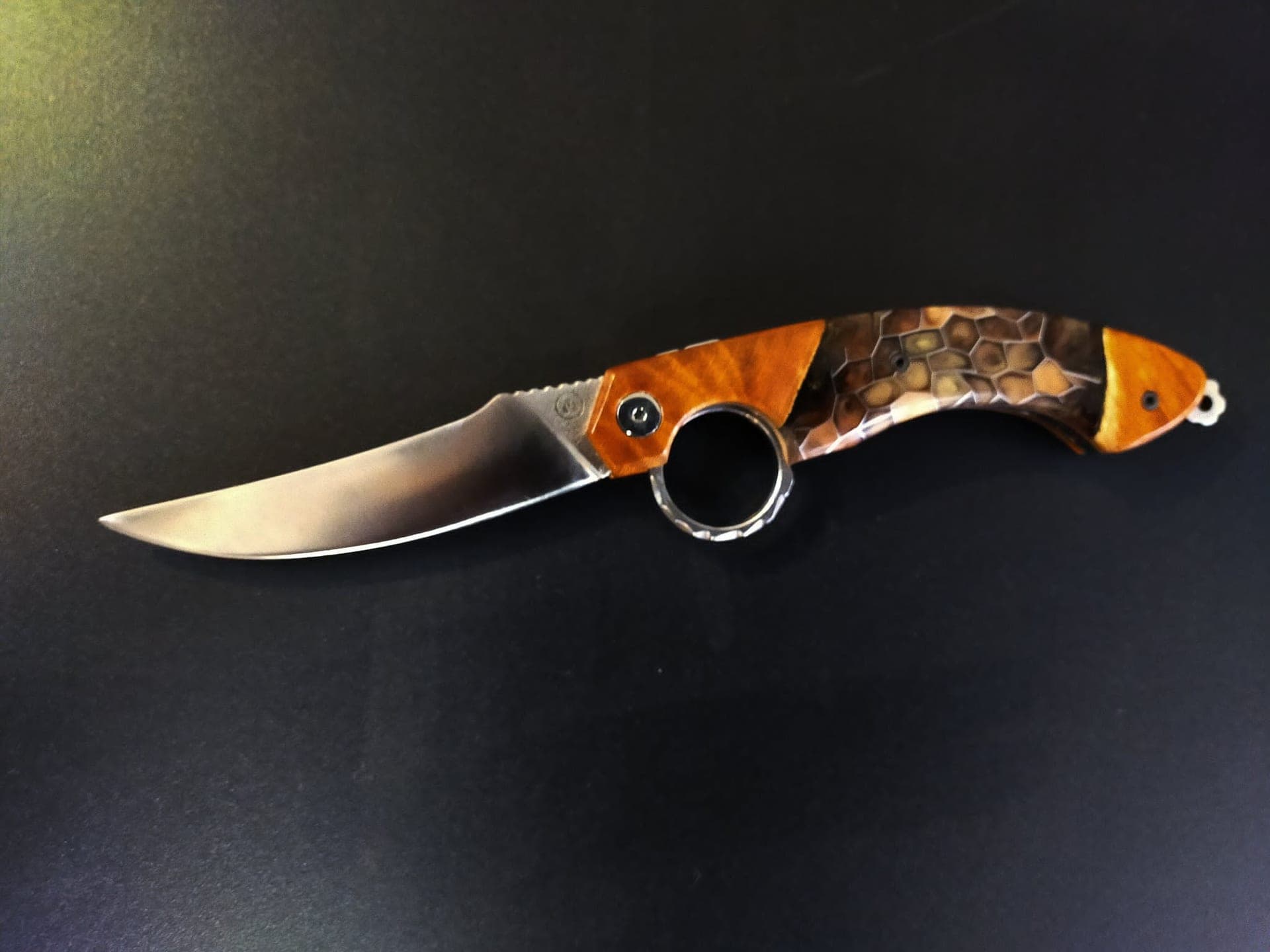 Le Mancharicou fermé, manche hybride associant un bois madré orangé et un nid d'abeille d'aluminium brun clair, anneau d'ouverture inversée au centre.
