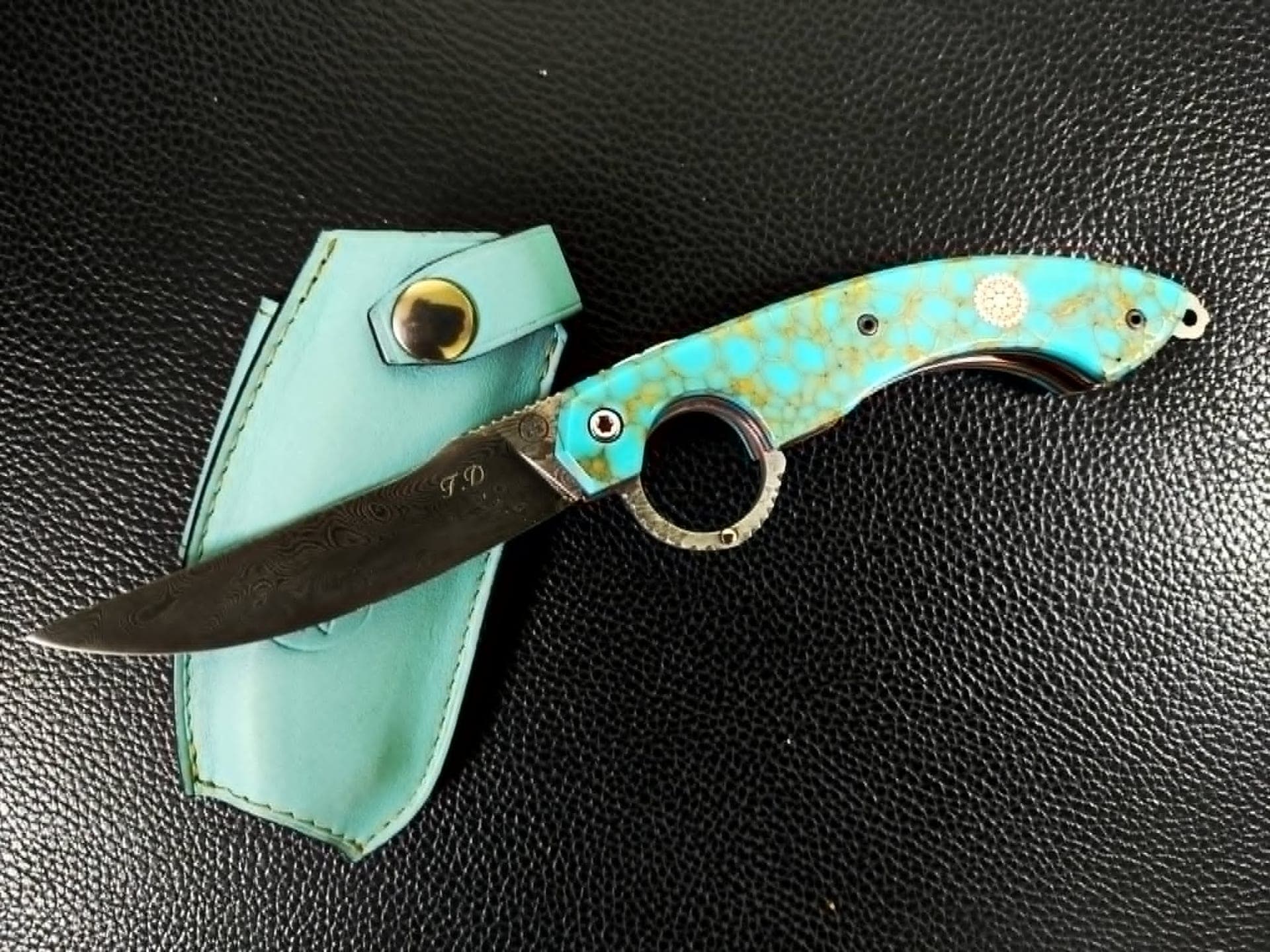 Le Mancharicou à lame damas gravée d'initiales, manche en turquoise reconstituée veinée d'or, avec son étui assorti.