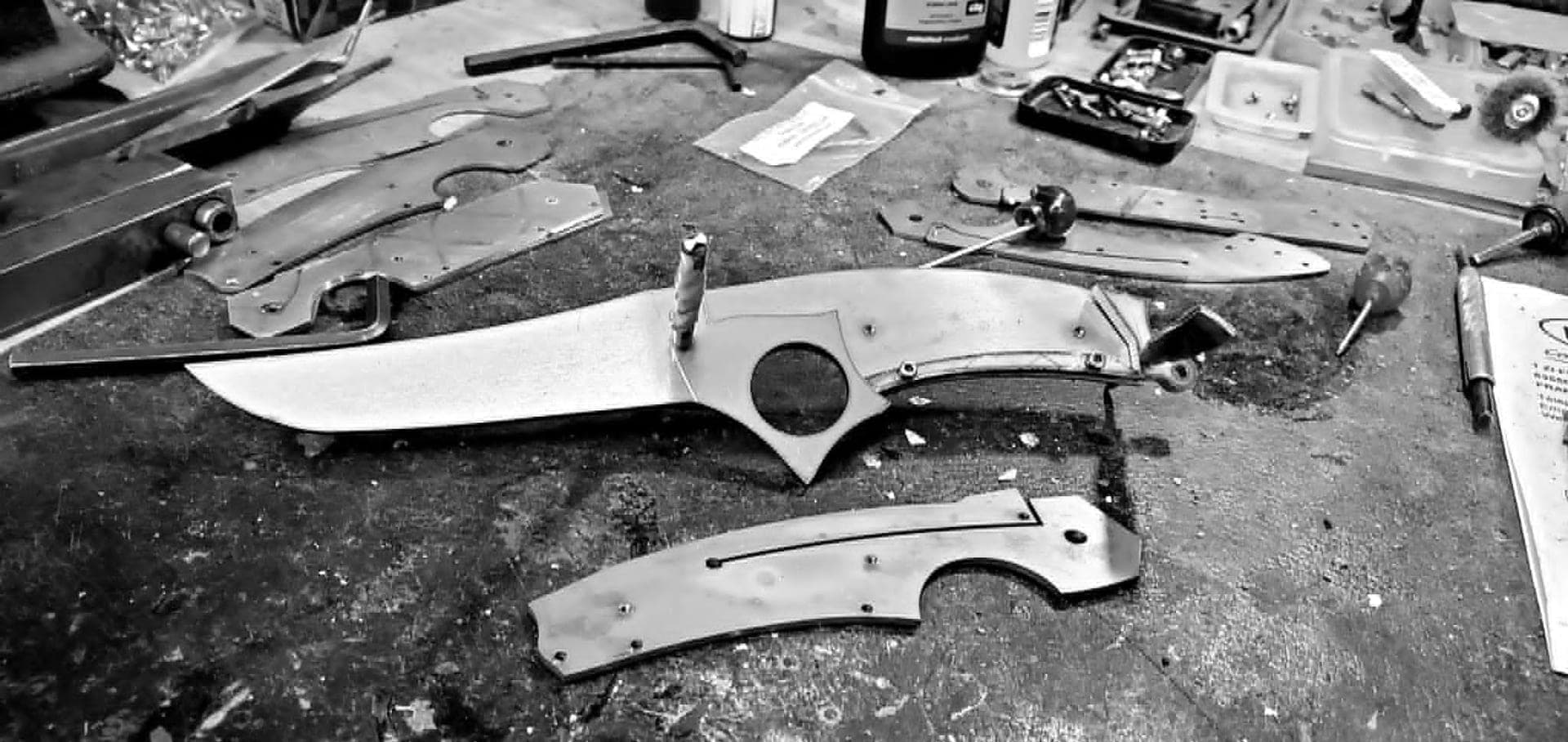 A cutlery workshop in Thiers: workbench, files and a blade being assembled under warm light.