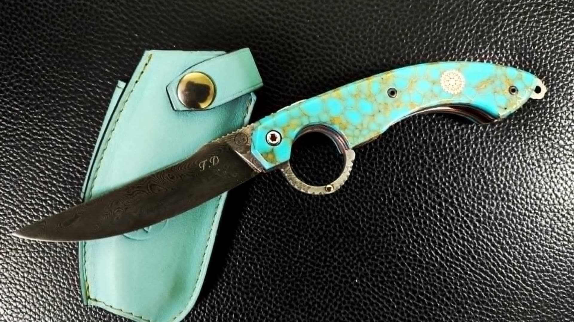 Photo réelle. Le Mancharicou à manche de turquoise reconstituée veinée d'or, lame damas gravée aux initiales, posé sur son étui turquoise assorti.